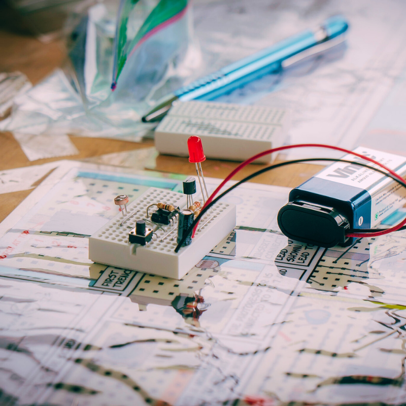 Maker Supplies including LEDs and breadboard on a workspace with tools and materials for DIY projects.
