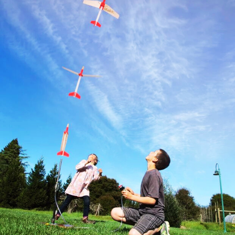 Children launching toy rockets in a field, exploring their passion for Rocketry.