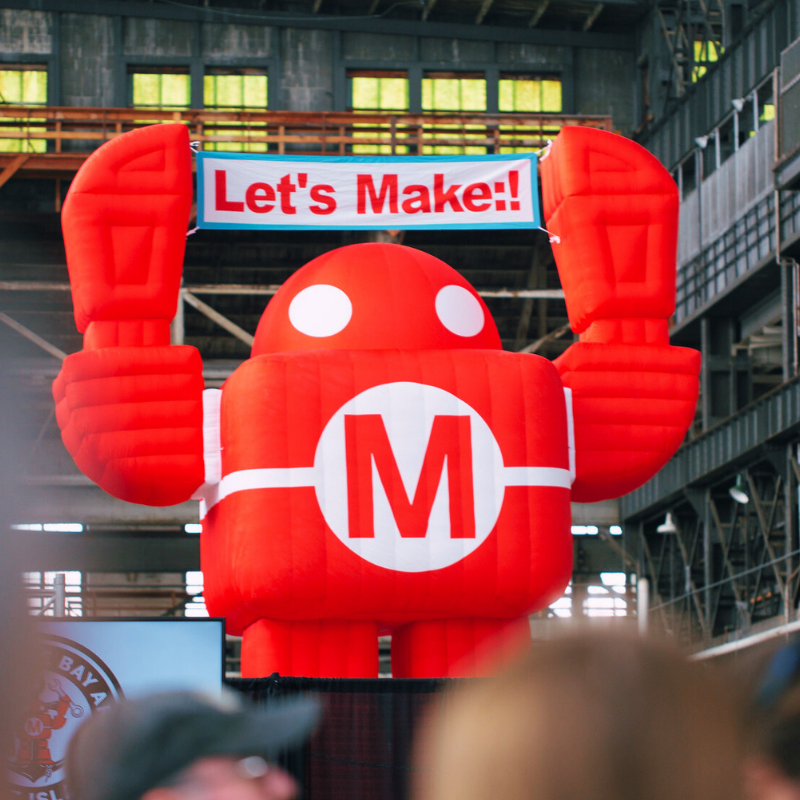 Inflatable robot mascot at Super Sale event with banner: "Let's Make!!" promoting maker gear and kits.