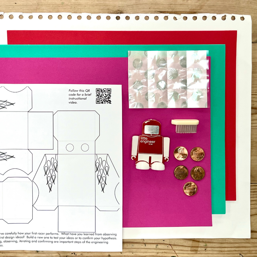 STEM Kits - Pizza Racer project materials including colorful sheets, a robot figure, and coins for engineering experiments.
