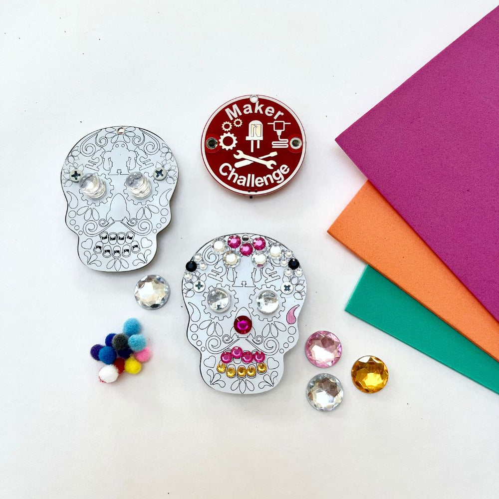 Learn To Solder - Sugar Skull kit components including decorated skulls, pom poms, and colorful paper.