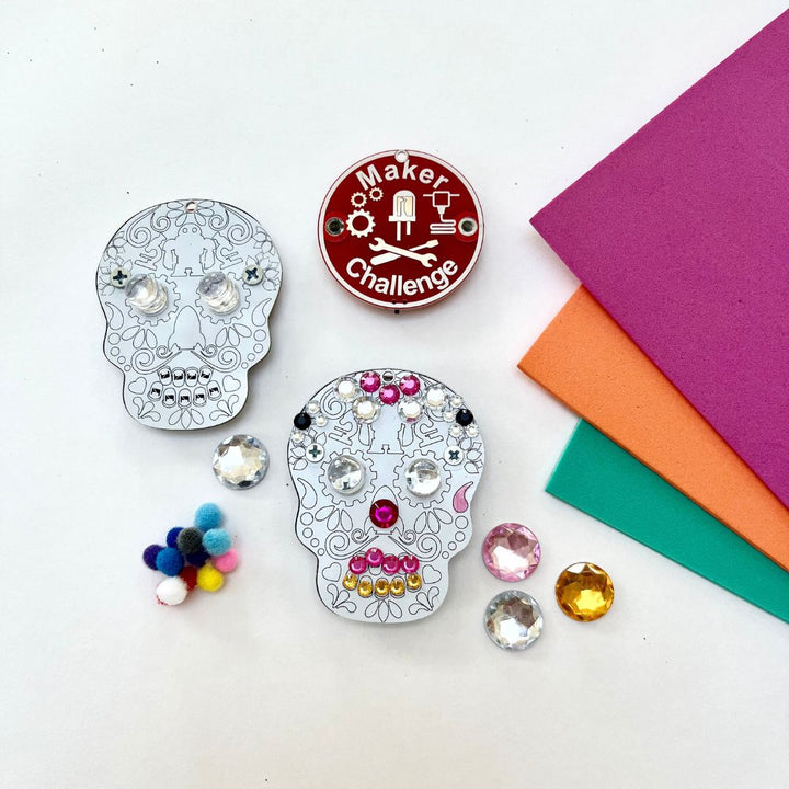 Learn To Solder - Sugar Skull kit components including decorated skulls, pom poms, and colorful paper.