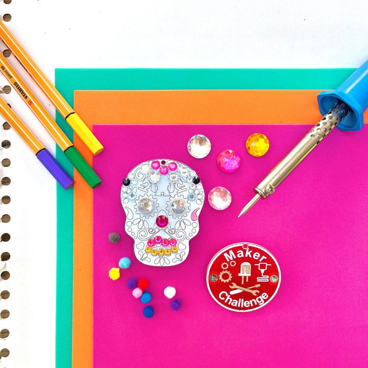 Learn To Solder - Sugar Skull kit including colorful decorations, soldering iron, and circuit components.