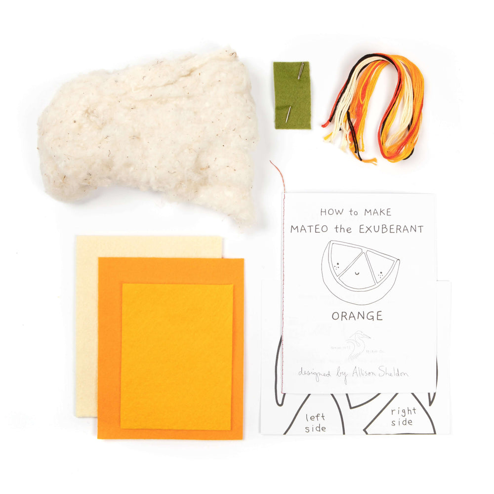 Materials for Mateo the Exuberant Orange Felt Stitching Kit including felt, stuffing, and instructions.