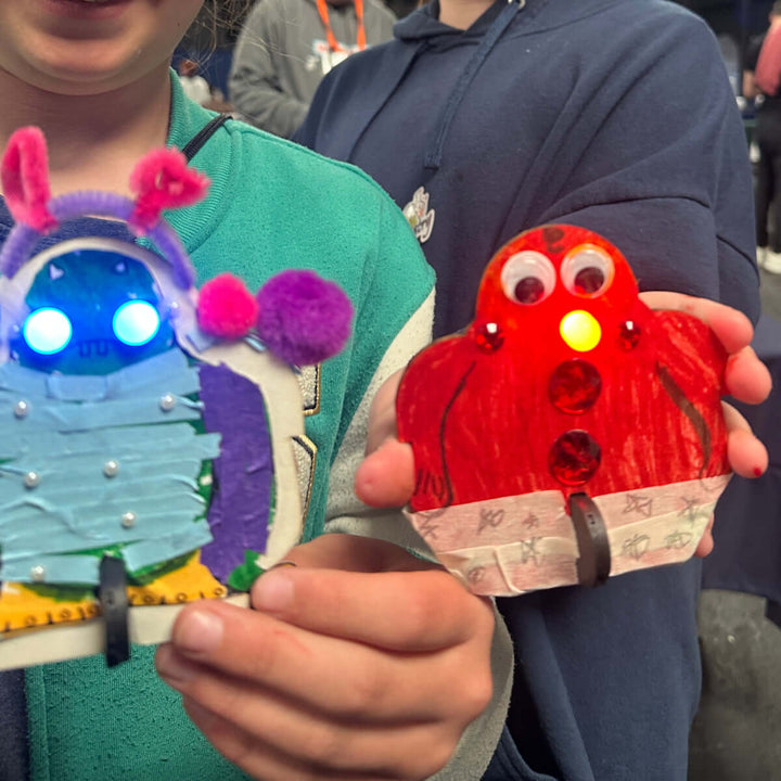 Two children with colorful craft projects in an indoor setting