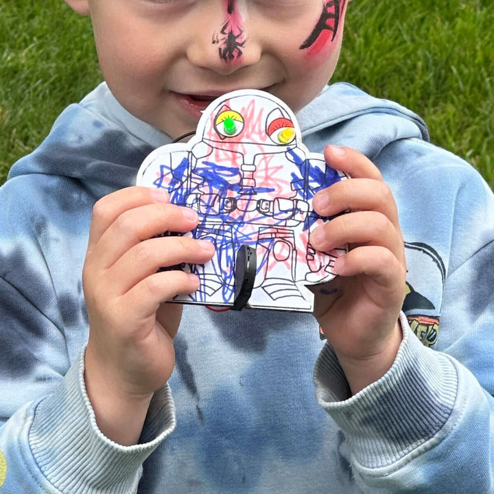 Child holding a colorful object at a Maker Faire event on grass