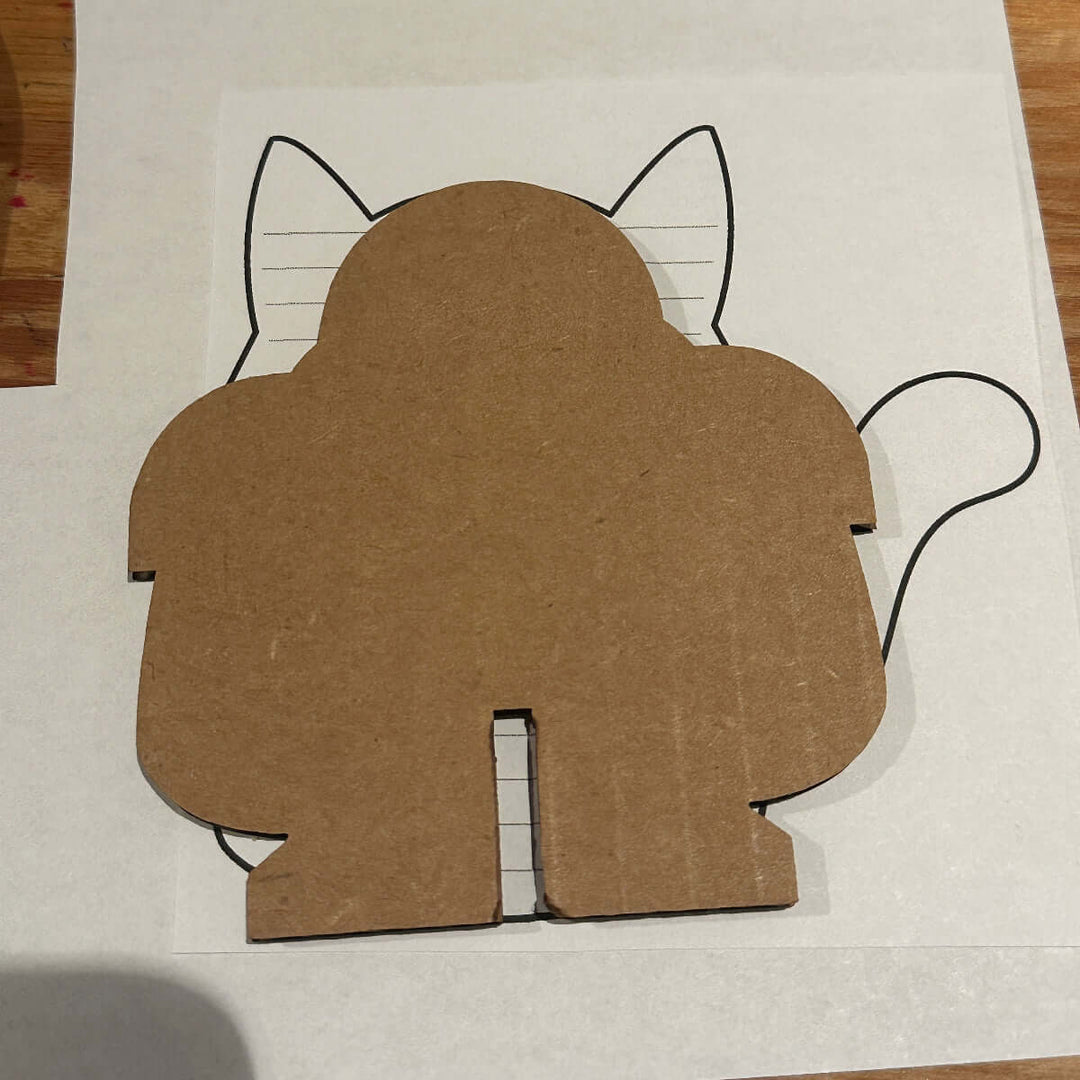 Cardboard cutout with a cat shape template on a white sheet of paper