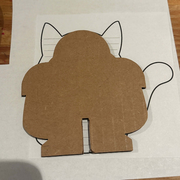 Cardboard cutout with a cat shape template on a white sheet of paper