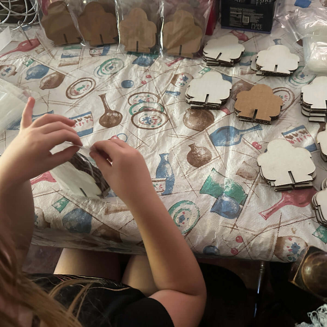 Person bagging robot shaped cardboard craft projects on a patterned tablecloth.