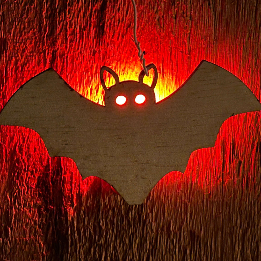 Bat-shaped decoration with glowing red eyes on a textured wooden background