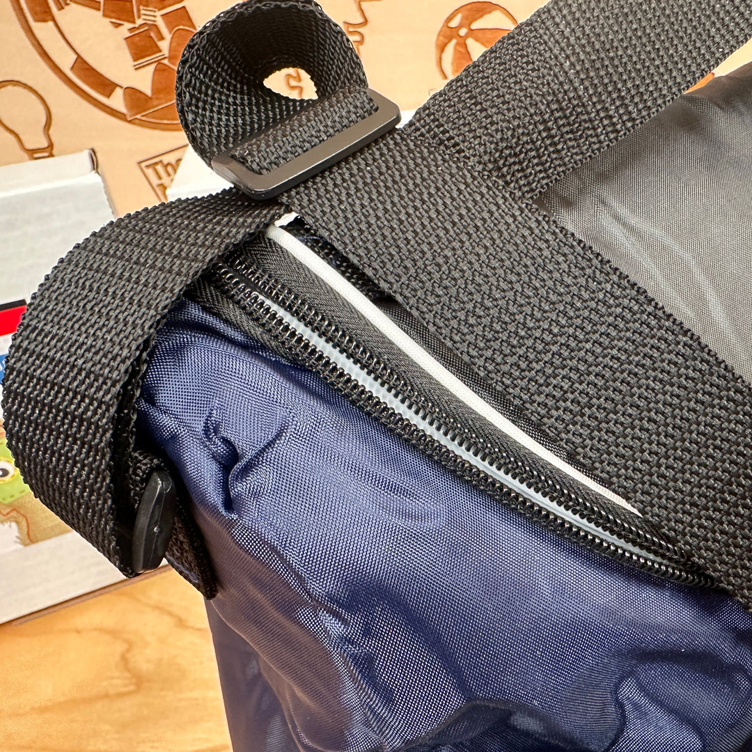 Close-up of a black strap and zipper on a blue bag with a patterned background