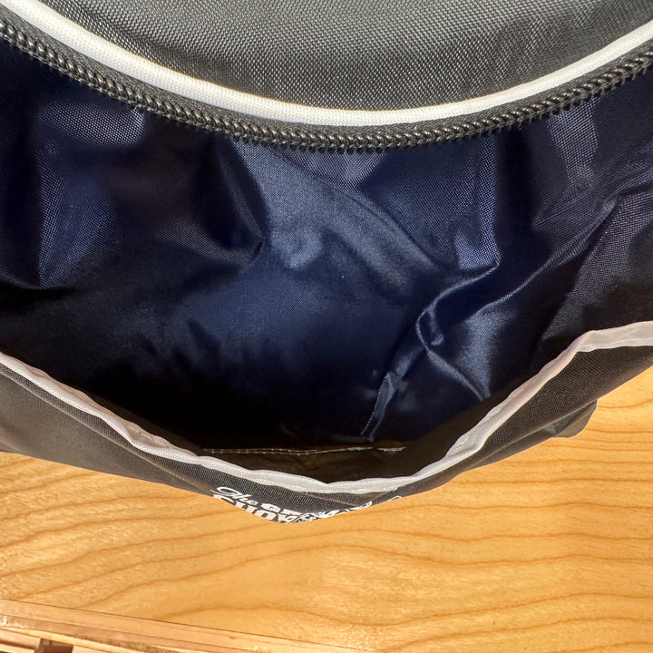 Close-up of a Maker Faire navy cooler bag front pouch on a wooden surface