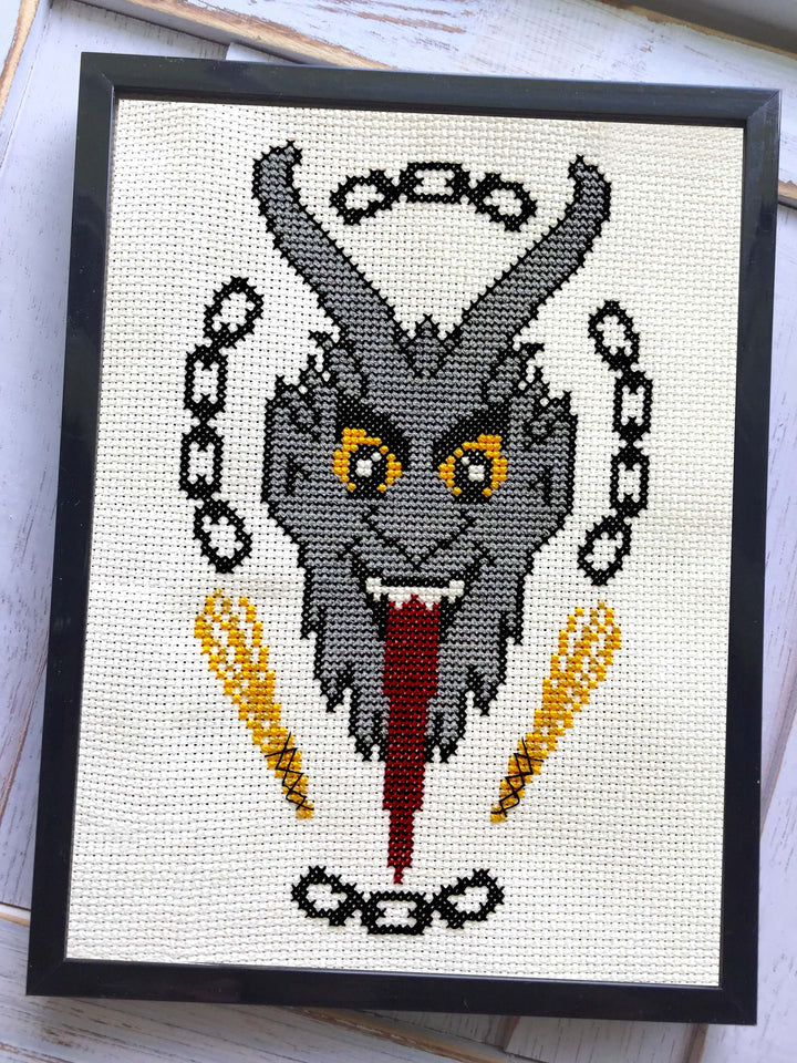 The Krampus Counted Cross Stitch DIY Kit finished design featuring a menacing Krampus portrait in a frame.
